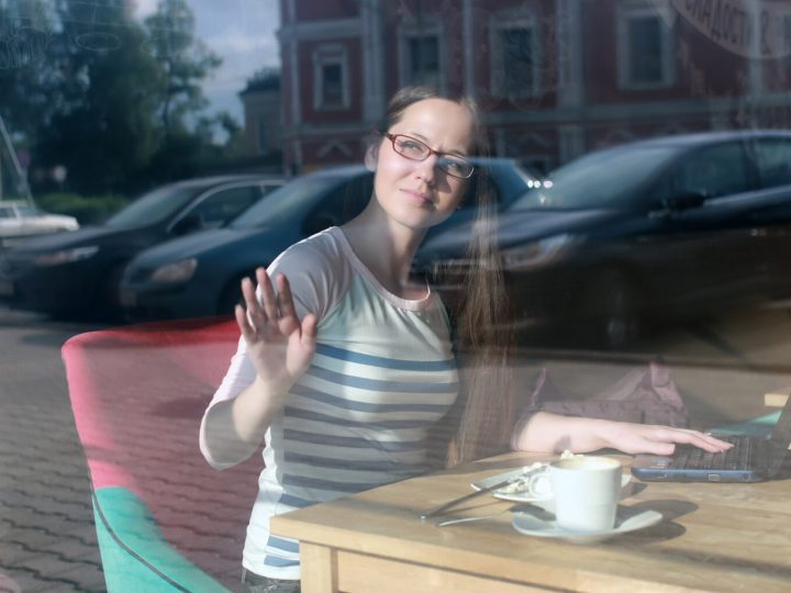 Mujer joven viendo por la ventana, en una cafetería